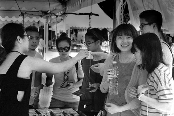 Grupo de jovens a conviver enquanto fazem compras na feira de artesanato de Macau.