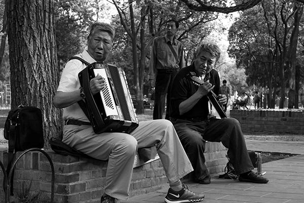 Homens a conviverem enquanto tocam instrumentos musicais, no Yu Garden em Shanghai.