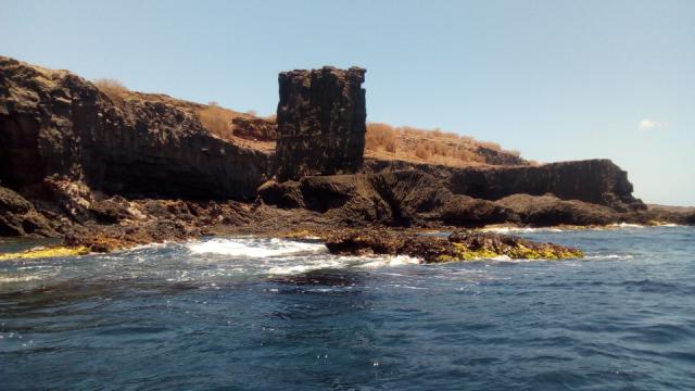 Um rochedo de formato paralelipipedo pode ser visto junto ao mar.