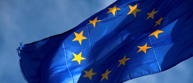 Bandeira da União Europeia num plano com o céu azul atrás.