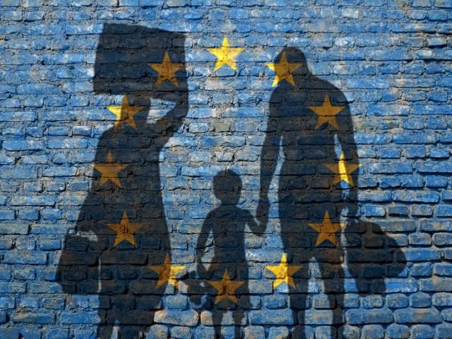 Sombras de emigrantes numa parede pintada com as cores da UE.